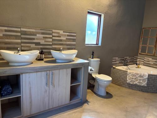 a bathroom with two sinks and a toilet and a tub at Shiandi Cottage in Hoedspruit