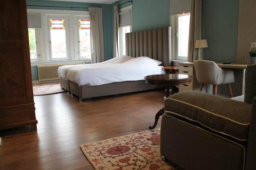 a bedroom with a bed and a couch and a table at B&B de Pastorie Terneuzen in Terneuzen