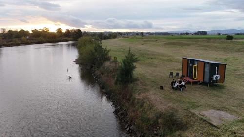 a tiny house sitting next to a body of water at Oscars Retreat 1 by Tiny Away in Raworth
