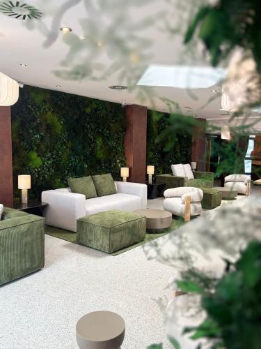 a living room with couches and tables and plants at Hotel Junior by OasiGroup Hotels in Rimini