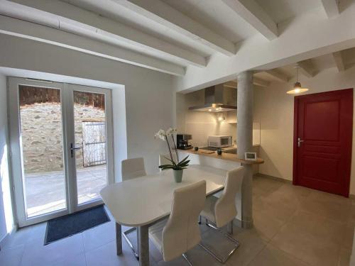 a kitchen and dining room with a white table and chairs at Le réveil des oiseaux in Taillet