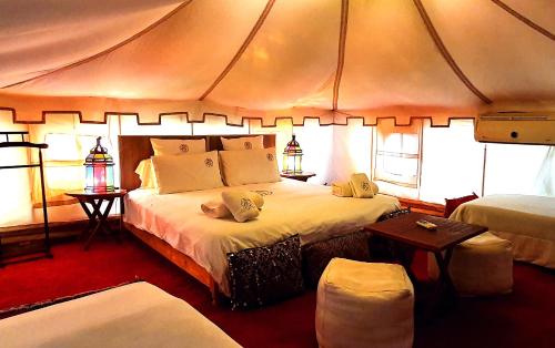 a bedroom with a large bed in a tent at Domaine Couleurs Berbères, Piscine, Vue Atlas, Bivouac & Expériences à Lalla Takerkoust in Lalla Takerkoust