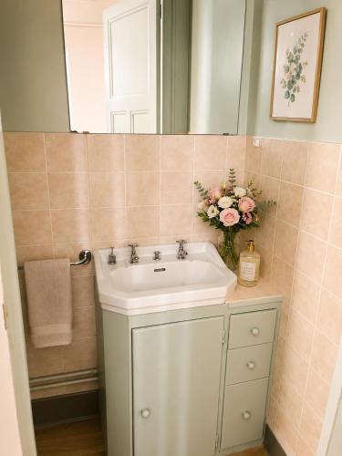 a bathroom with a sink and a mirror and flowers at Le boudoir de Marie in Montluçon