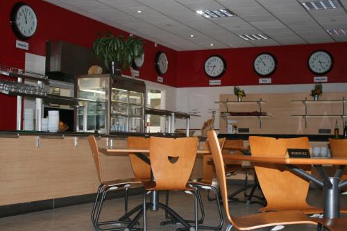 un restaurant avec une table, des chaises et des horloges dans l'établissement Résidence Universitaire Lanteri, à Fontenay-aux-Roses