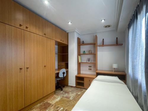 a bedroom with a bed and wooden cabinets and a desk at Dúplex 2 plantas en Centro histórico de Elche in Elche