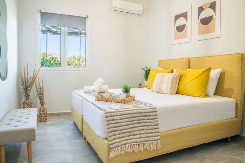 a bedroom with a large bed with yellow pillows at Dafni Villa a place to visit by Rentado in Orné