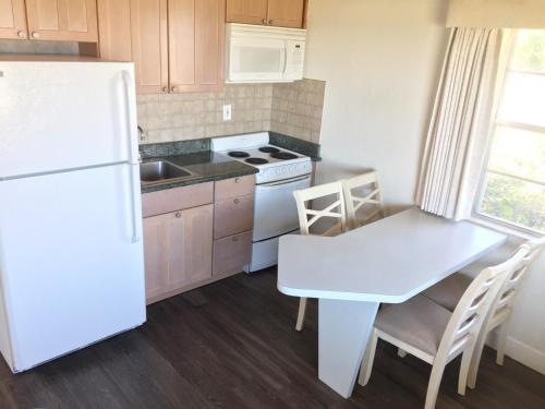 a kitchen with a white refrigerator and a table at Surf Studio Beach Resort in Cocoa Beach