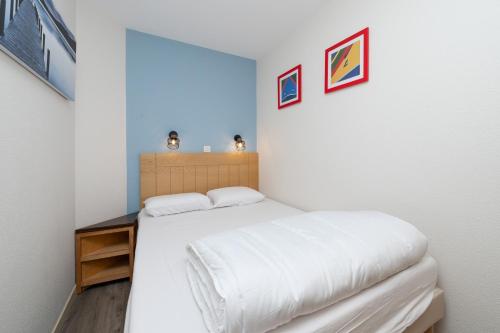 a bedroom with a white bed with a wooden table at Appartement 4p - piscine partagée in Arzon
