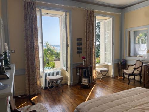 a bedroom with a bed and two large windows at Manoir Mer & Pins in Fouesnant