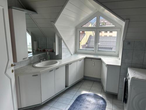 a white bathroom with a sink and a window at Bergblick Apartment in Lienz