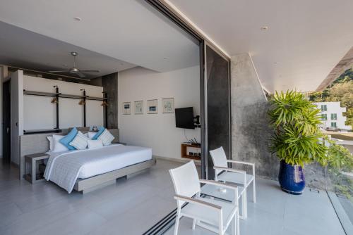 a bedroom with a bed and two chairs and a tv at Villa Momo seaview pool & game room Kata in Kata Beach