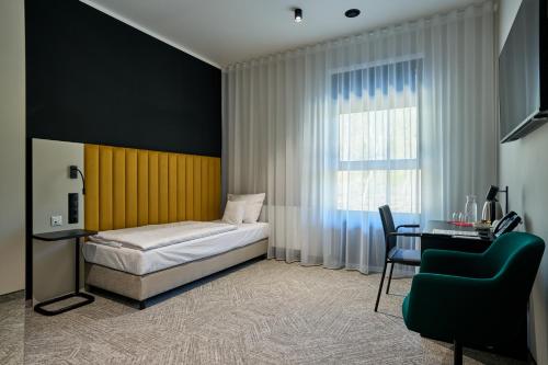 a bedroom with a bed and a desk and a window at Hotel Nowa Bukowa in Katowice