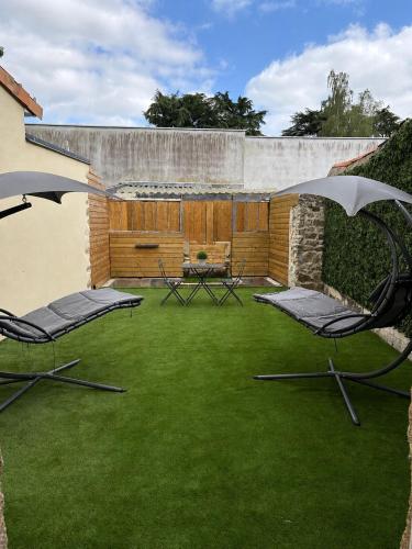 two chairs and an umbrella on a yard with grass at La Romantique in Bressuire