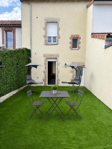 a patio with a table and chairs on the grass at La Romantique in Bressuire