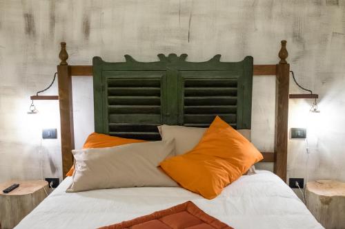a bed with a green headboard and orange pillows at ViaBasso11 Guest House in Novi Ligure