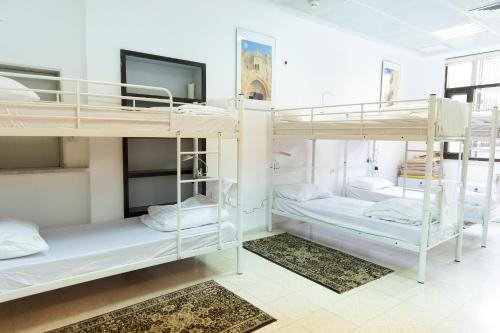 a room with three bunk beds with a tv at New Gate Hostel in Jerusalem