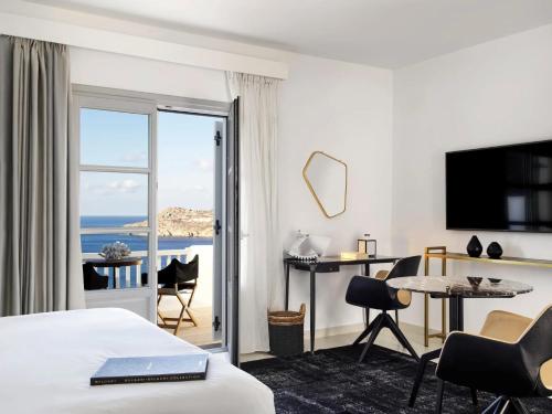 a hotel room with a bed and a view of the ocean at Myconian Villa Collection - Preferred Hotels & Resorts in Elia Beach