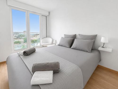 a white bedroom with a large bed with a window at Porte de Paris, spacieux T3, terrasse et parking in Vanves