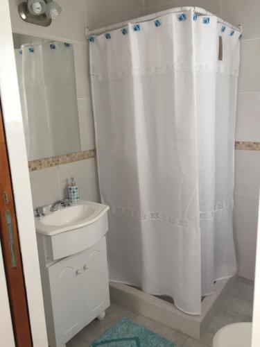 a bathroom with a white shower curtain and a sink at Soñada in Tandil