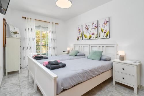 a white bedroom with two beds and a window at Club Oasis Flat in Málaga
