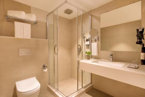 a bathroom with a shower and a toilet and a sink at Regenta Place CG Road in Ahmedabad