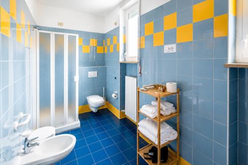 Ein blau-gelbes Badezimmer mit Toilette und Waschbecken in der Unterkunft Phi Hotel Homy Druento in Druento