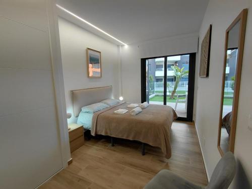 a bedroom with a bed and a large window at Private Garden Apartment - Villamartin, Orihuela Costa in Villamartin