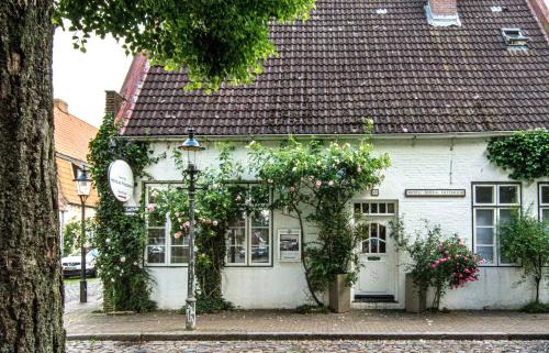 a white building with flowers in front of it at Herzog Friedlich Hotel Garni in Friedrichstadt