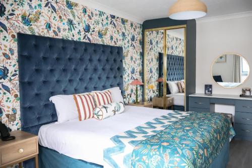a bedroom with a large bed with a blue headboard at Hotel Collingwood BW Signature Collection in Bournemouth