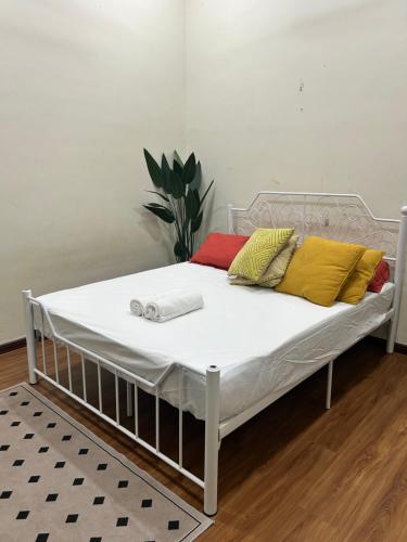a bed with yellow and red pillows on it at NovaStay Melaka in Kampong Kerubong