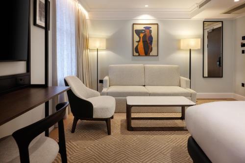 a hotel room with a bed and a couch and a table at Radisson Blu Hotel, London Bloomsbury in London