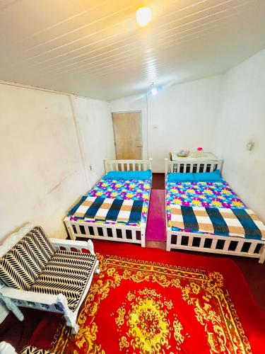 two beds in a room with a red rug at Peradeniya Inn in Kandy