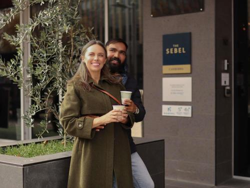 a man and a woman standing in front of a building at The Sebel Canberra Civic in Canberra