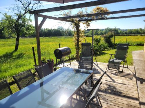 a patio with a table and chairs and a grill at Les Gîtes de la chapelle blanche in Anor