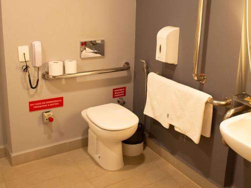 a bathroom with a toilet and a sink and towels at ibis Parauapebas in Parauapebas