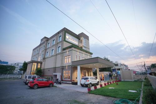 a building with cars parked in a parking lot at Hotel Grand Vekasa in Salem