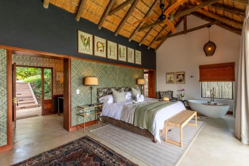 a bedroom with a bed and a tub and a sink at Buhala Lodge in Malelane