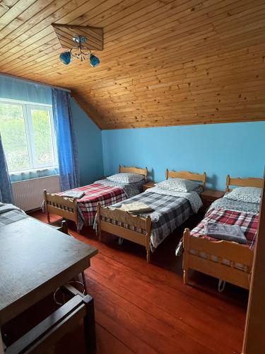 a room with three beds and a wooden ceiling at Villa Maria in Slavske