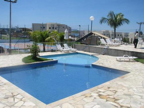 una gran piscina azul con sillas y árboles en Apto Cabo Frio Marina Clube, en Cabo Frío