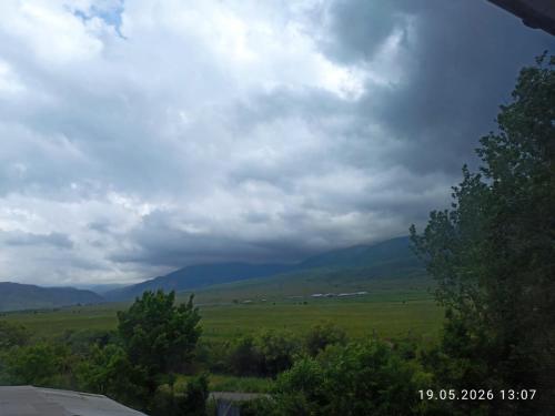 a view of a green field with mountains in the distance at Village House in Zhabagly