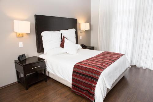 Habitación de hotel con cama grande con sábanas y almohadas blancas. en Suites Ganges, en Ciudad de México