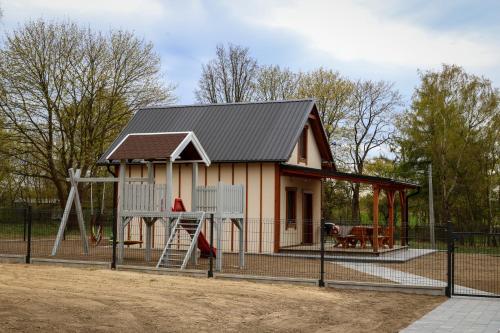 a small house with a playground and a play structure at Przystanek Semlin - Za Jeziorem in Semlin
