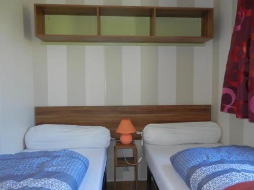 a room with two beds and a lamp on a table at Camping 3 étoiles - Piscine - ccbgaig in Loubeyrat