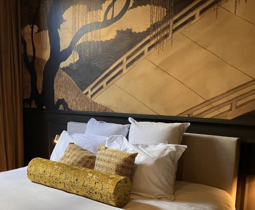 a bed with white pillows and a painting on the wall at Gilded Ox Suites in Deventer
