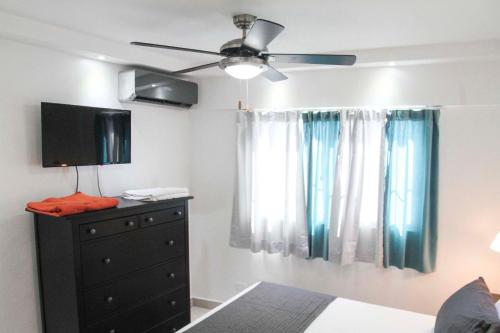 ein Schlafzimmer mit einem Deckenventilator und einer Kommode mit einem TV in der Unterkunft City Caribbean Hotel Boutique in Santo Domingo