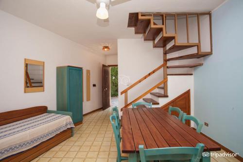 ein Esszimmer mit einem Holztisch und einer Treppe in der Unterkunft Villaggio Cala Verde in Copanello