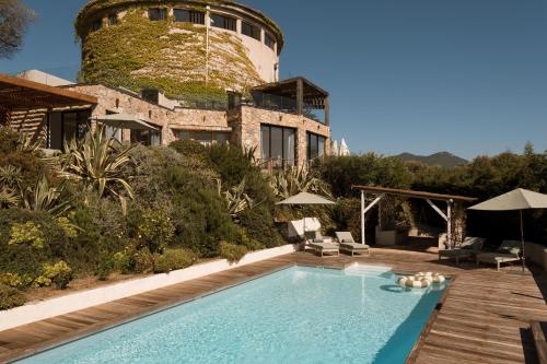 a pool in front of a building with a water tower at L'Hostellerie du Moulin des Oliviers in Olmeto