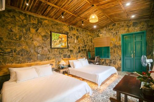 two beds in a room with a stone wall at Laco Green Trang An in Yên Ha