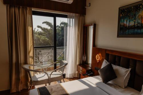 a bedroom with a bed and a chair and a window at The Twelve Petals by Parvati Inn in Dhikuli