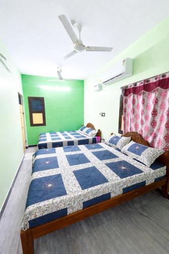 two beds in a room with green walls at CR Private Villa in Tiruvannāmalai